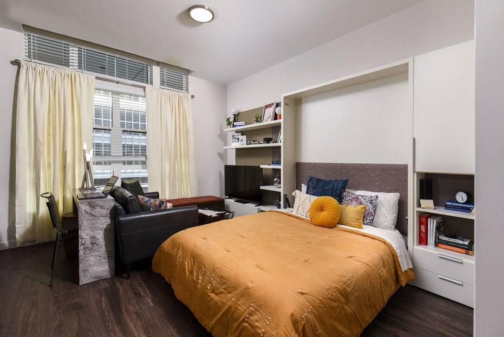 a bedroom with a bed and a desk in a room with a window