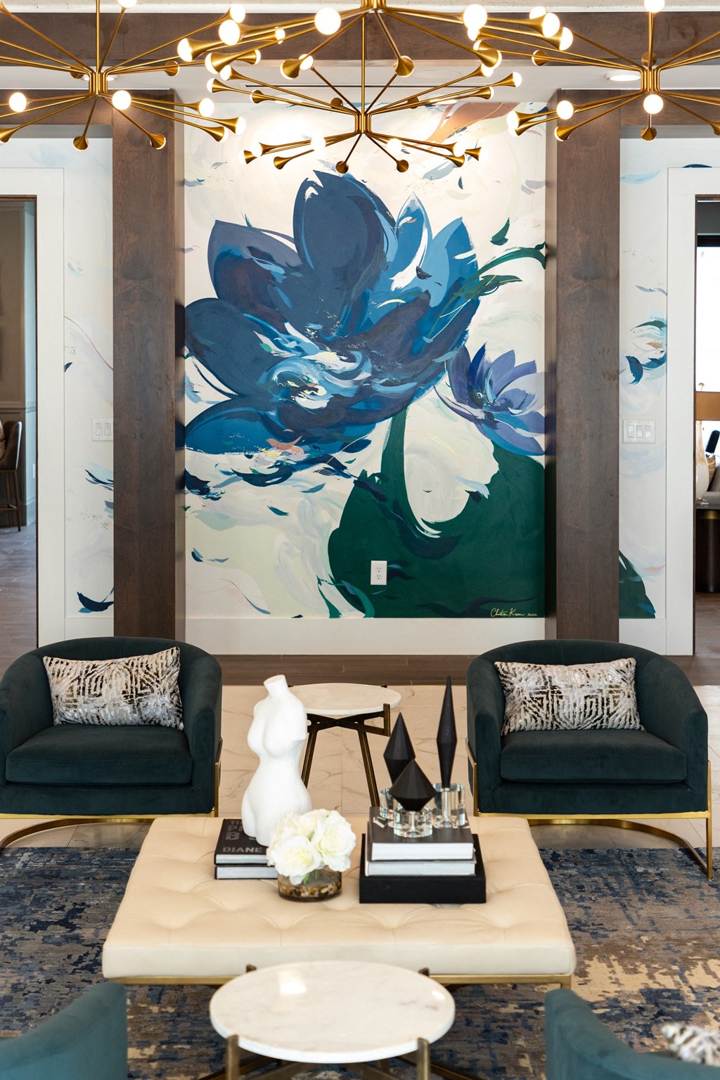 a living room with two blue chairs and a large painting on the wall