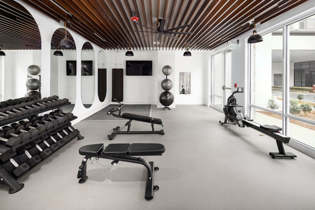 a workout room with weights and chairs and windows