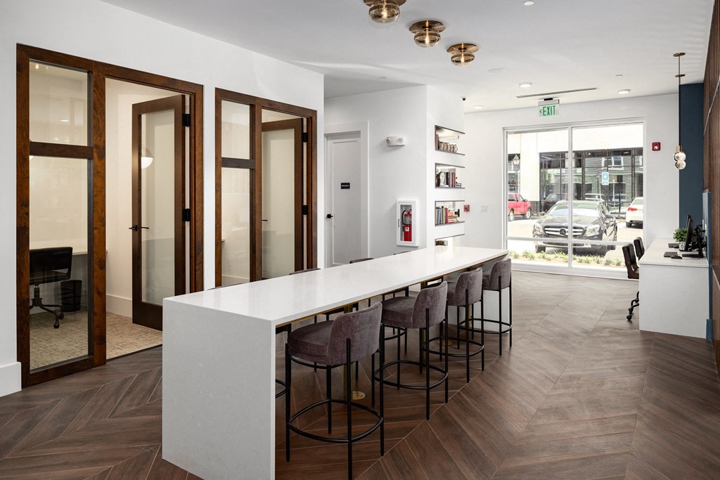 a kitchen with a long white counter top and a row of chairs