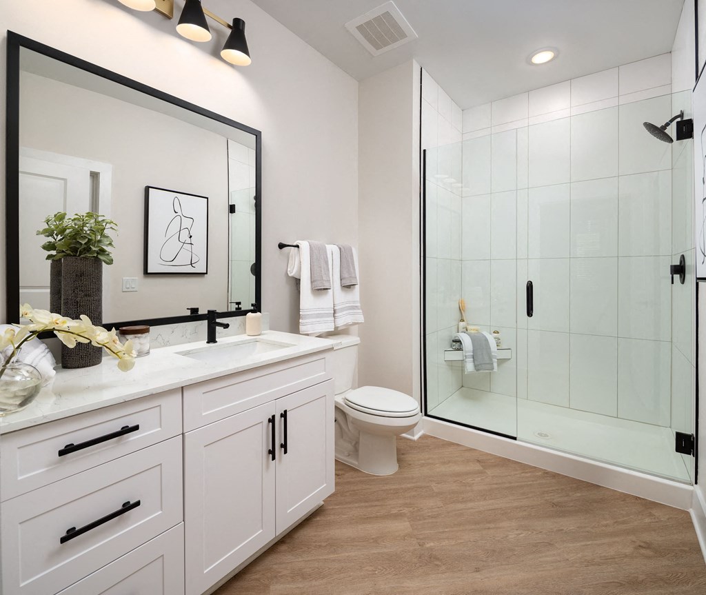 a white bathroom with a large mirror and a shower