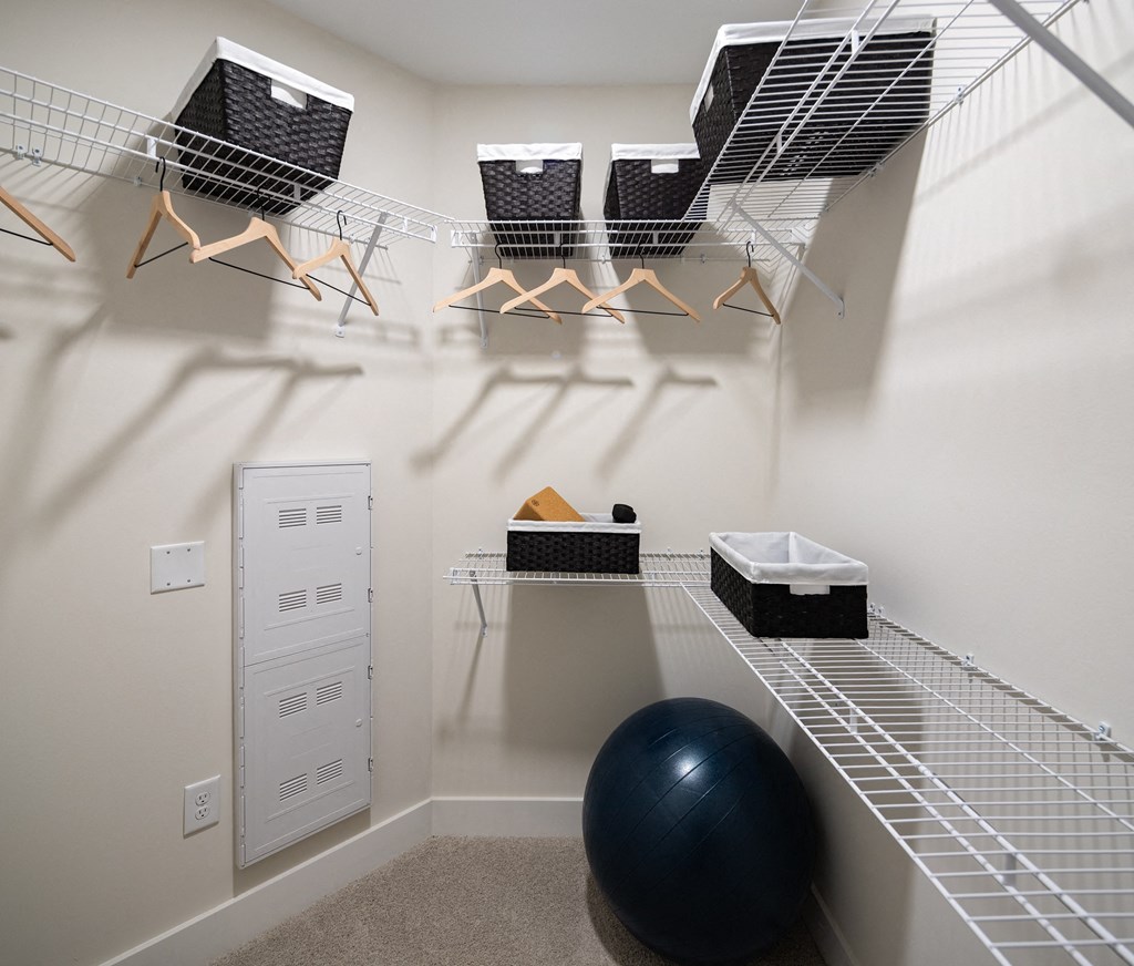 a spacious exercise room with a gym ball and shelves