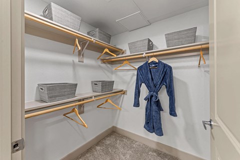 a walk in closet with coats and jackets on shelves and hooks