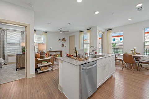 a kitchen with an island and a living room with a table and chairs