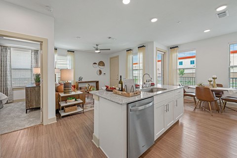 a kitchen with an island and a living room with a table and chairs