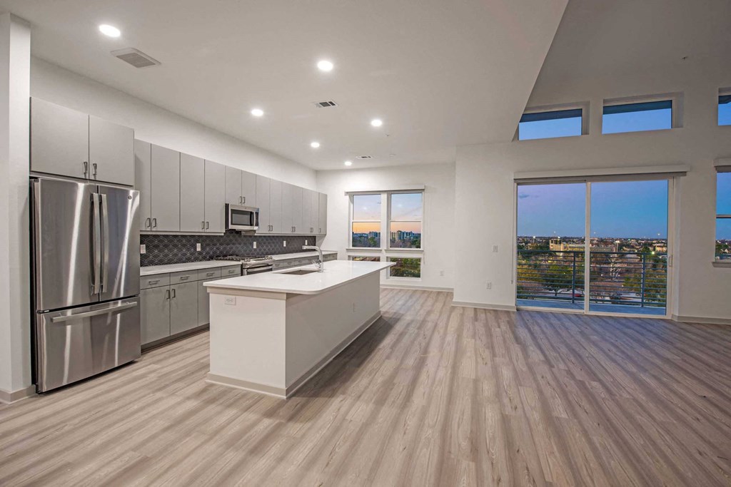 a kitchen with a large island and a stainless steel refrigerator
