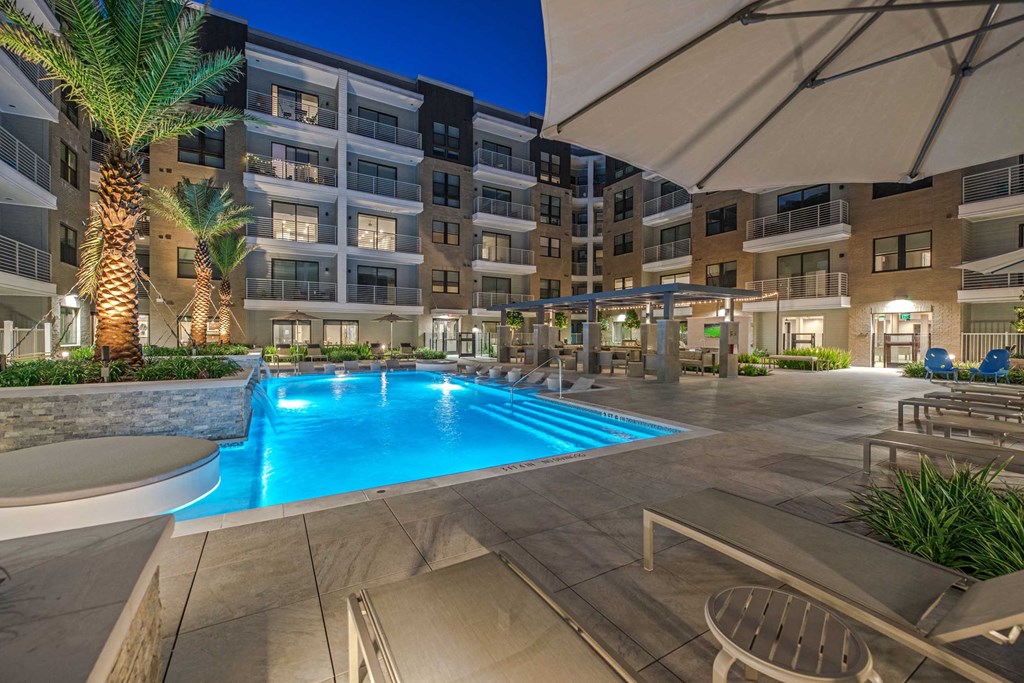a swimming pool at night in a large apartment building with a pool