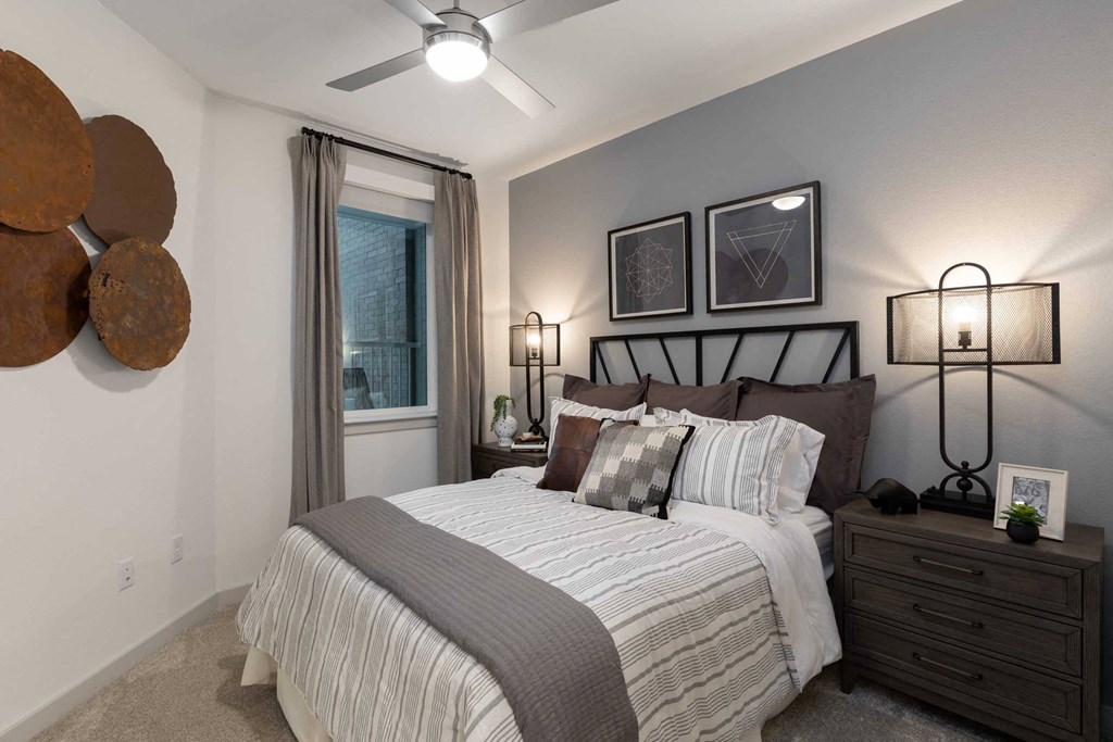 bedroom with ceiling fan and window in a model home