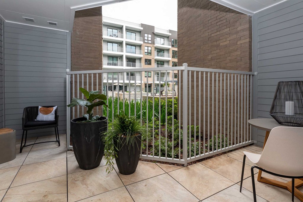 a balcony with chairs and plants and a fence