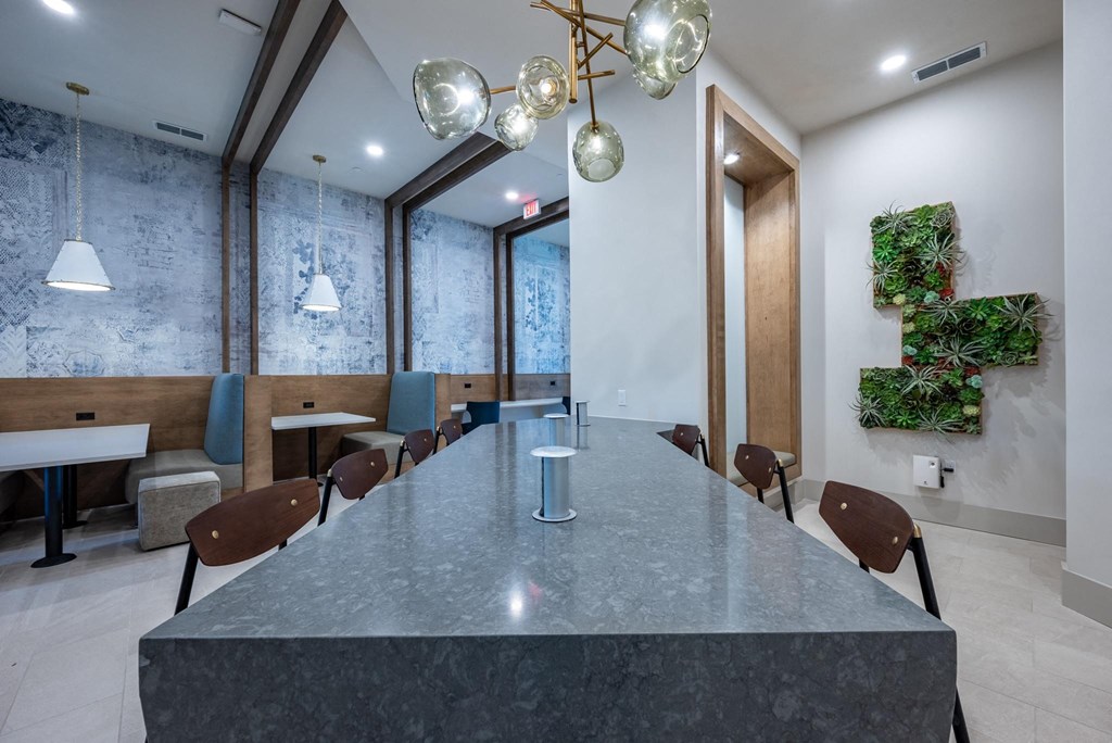 a long table in a dining room with chairs and a plant wall