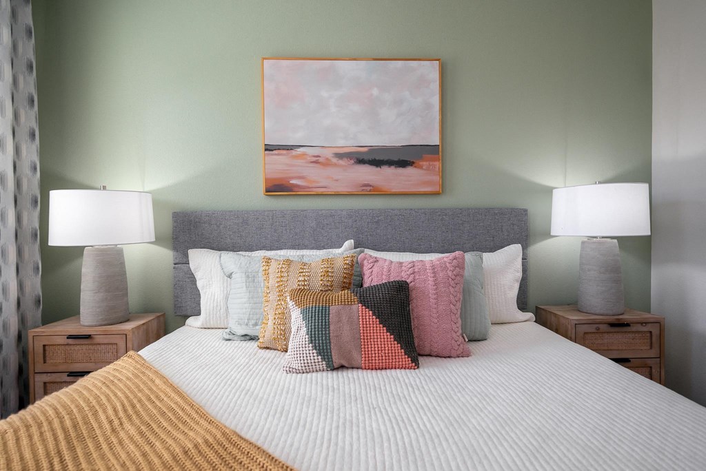 a bedroom with a bed with pillows and a painting on the wall