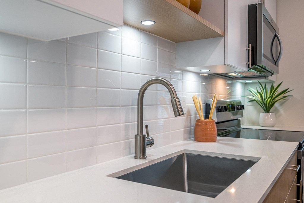 a white kitchen with a sink and a faucet