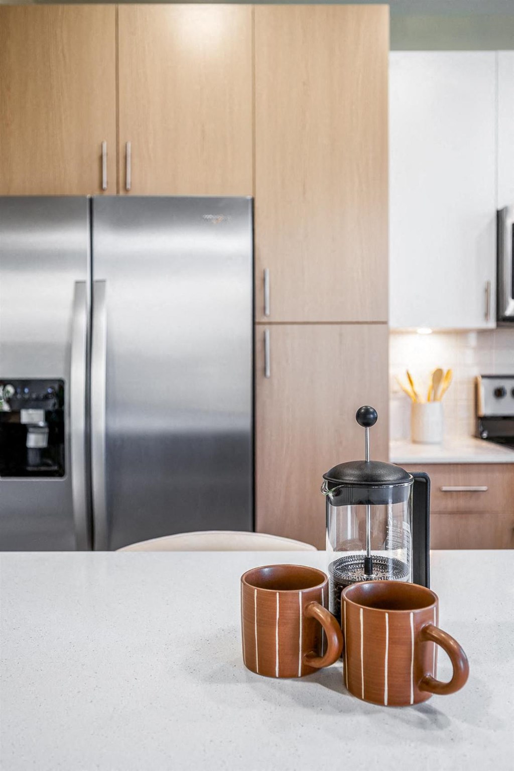a kitchen with a coffee maker and two cups on a counter