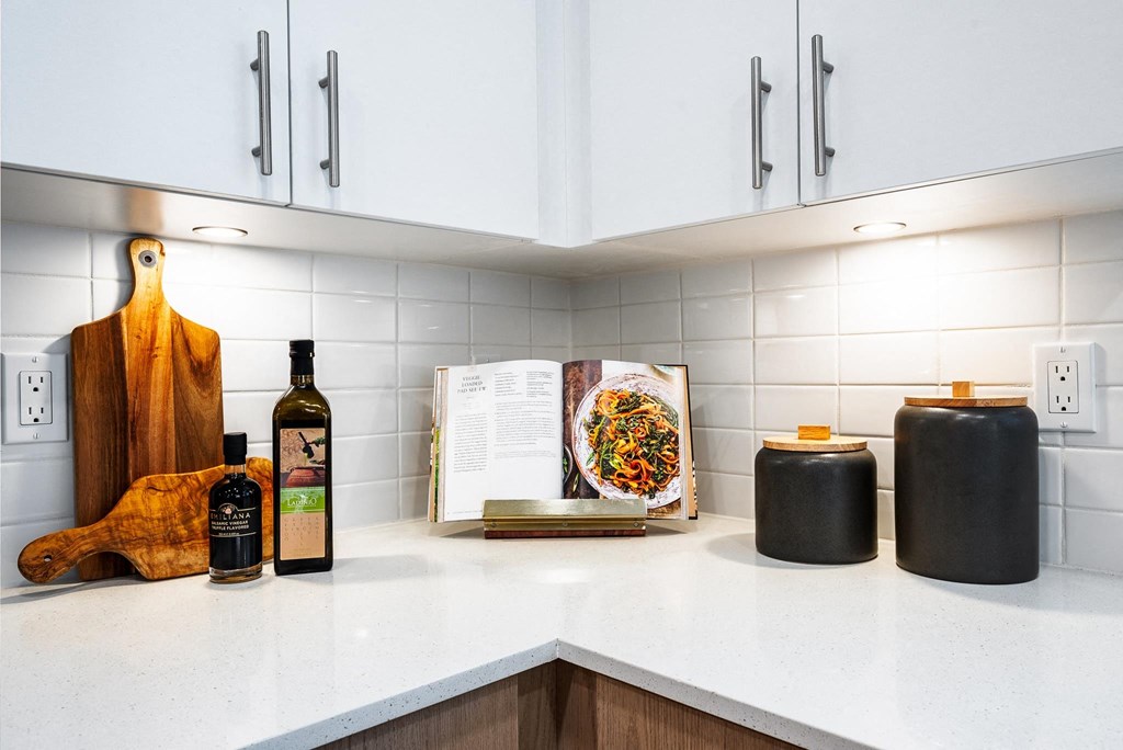 a kitchen counter with a cookbook and bottles of wine on it