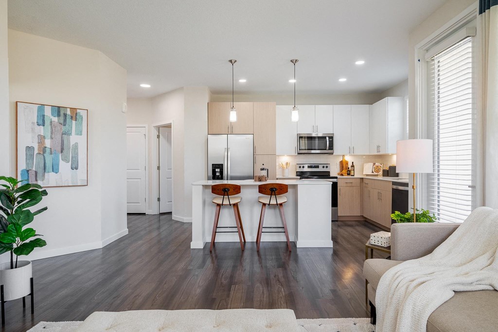 a living room with a kitchen with a bar and stools