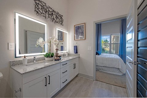 a bathroom with a large mirror and a door to a bedroom