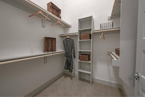 a walk in closet with a robe and shelves