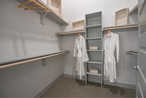 a walk in closet with white robes and shelves