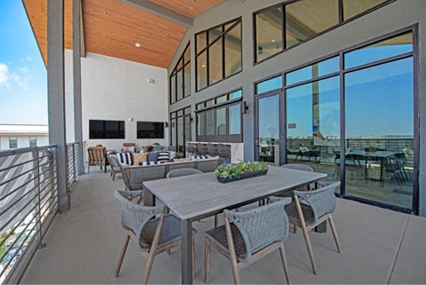 a patio with a table and chairs and large windows