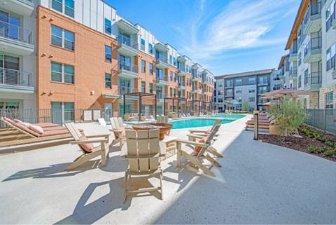 an outdoor patio with chairs and a pool at an apartment building