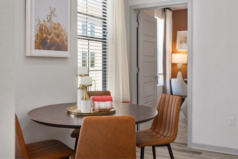 a dining room with a table and chairs and a door to a living room