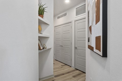a hallway with white doors and white walls and wood flooring
