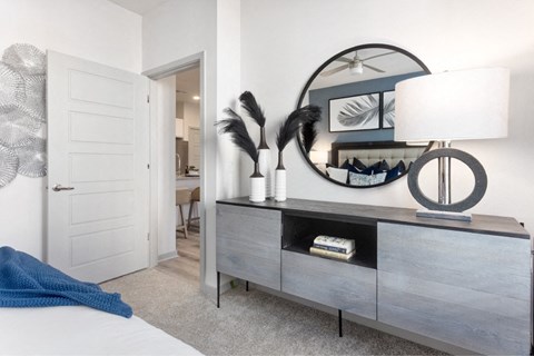 a bedroom with a dresser with a lamp and a mirror