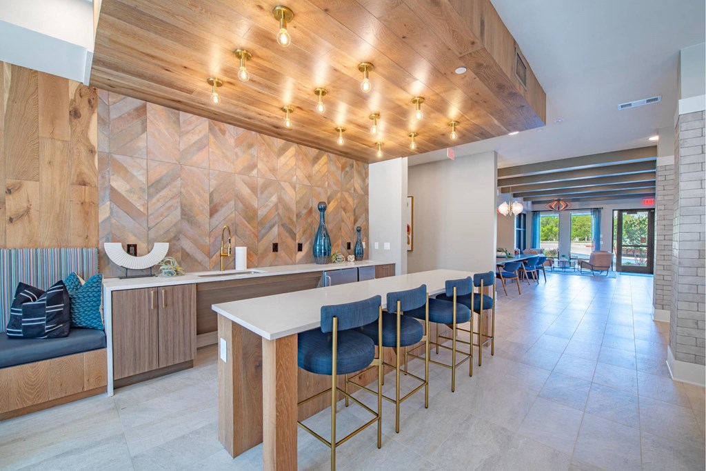 a bar with blue stools in a large room with a counter and chairs