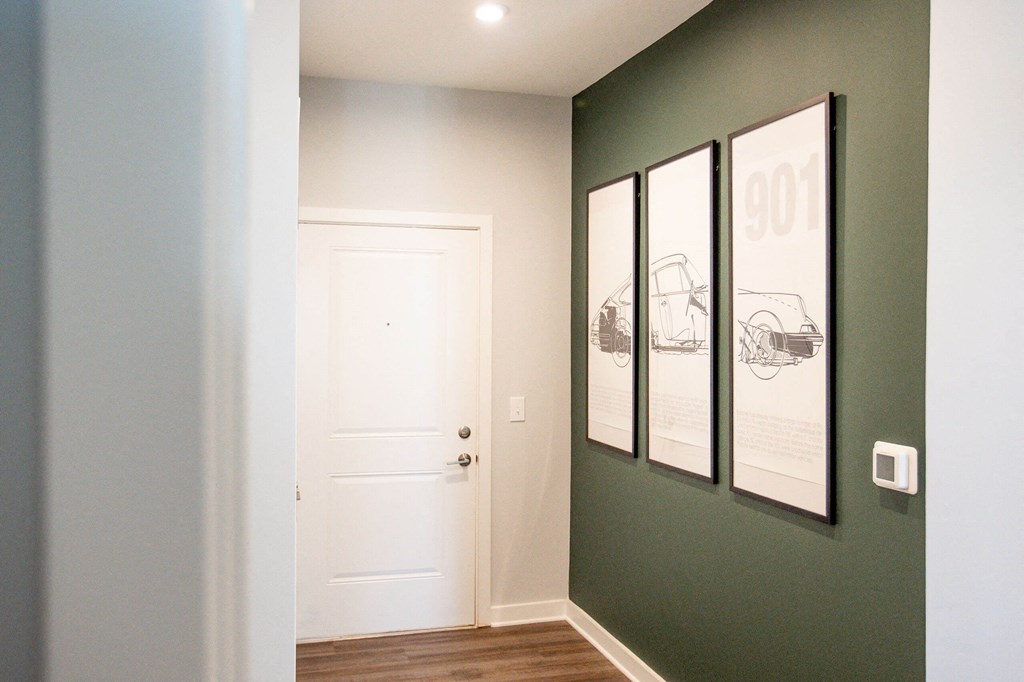 a hallway with a white door and three pictures on the wall