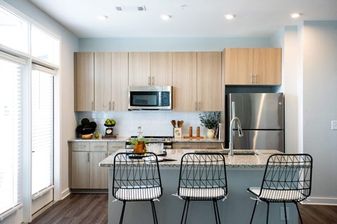 a kitchen with wooden cabinets and a counter with three chairs
