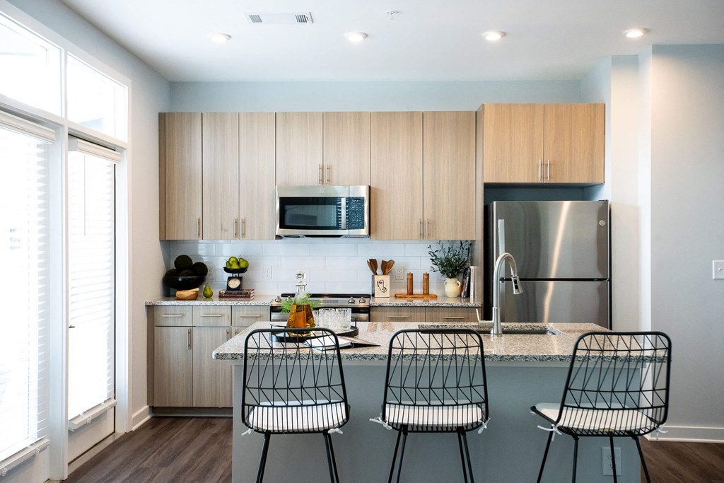 a kitchen with wooden cabinets and a counter with three chairs
