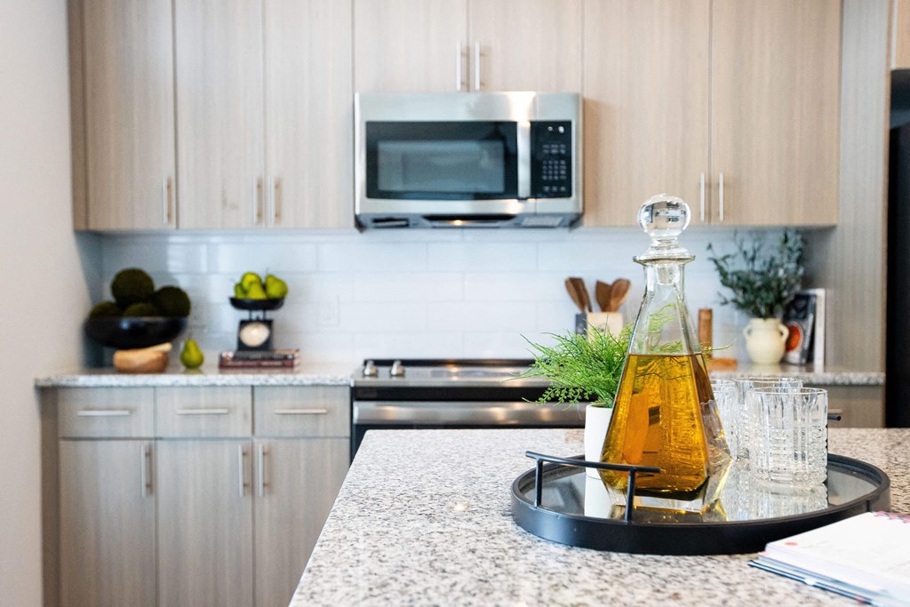a kitchen counter with a bottle of oil and glasses on it