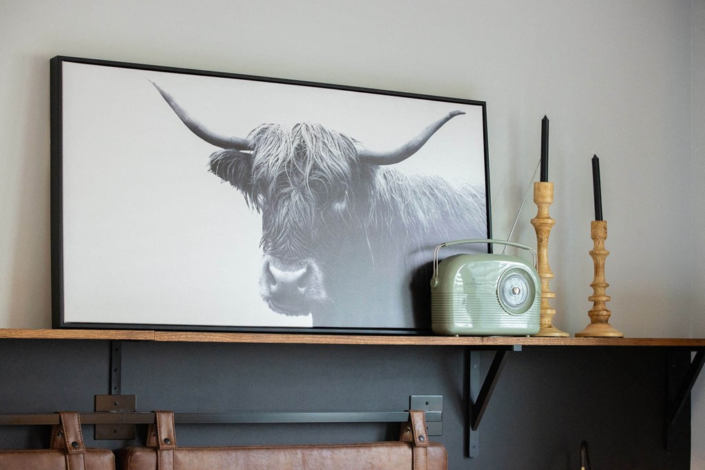 a painting of a cow on a shelf with a radio and a phone