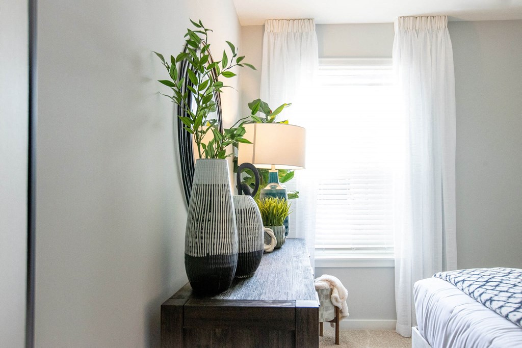 a bedroom with a table with vases and plants on it