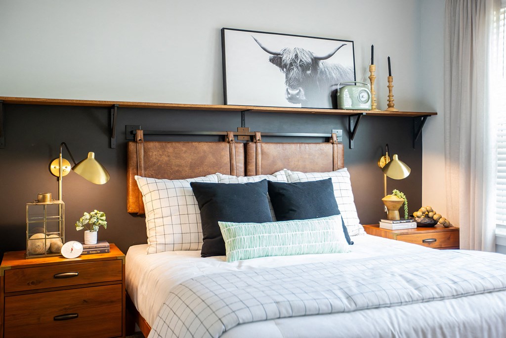 a bedroom with a bed with a wooden headboard and a painting of a bull