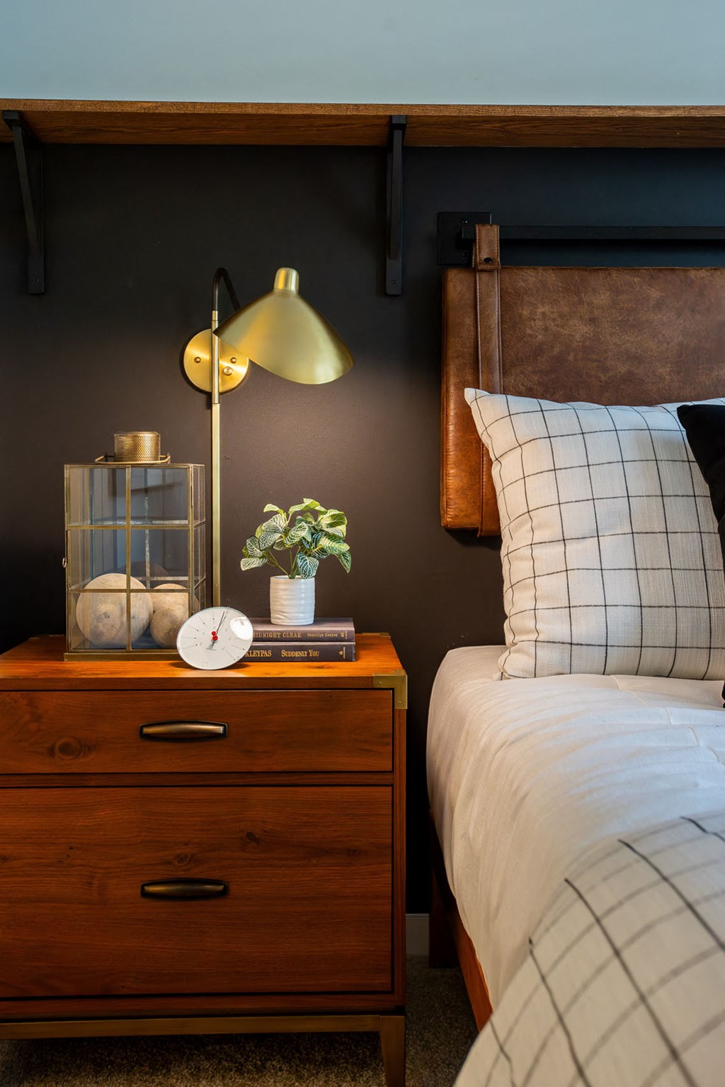 a bedroom with a bed and a nightstand with a clock and a lamp