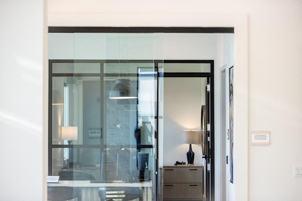 a glass door in a room with a desk and a lamp