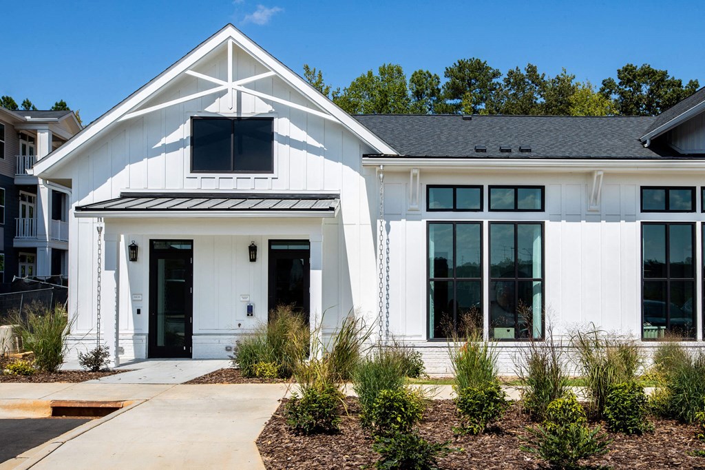 the exterior of a white house with a sidewalk and plants