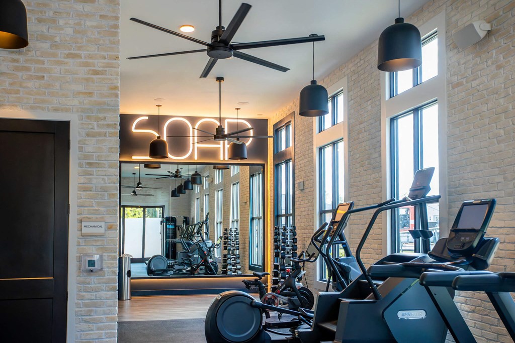 a gym with various workout machines and a ceiling fan