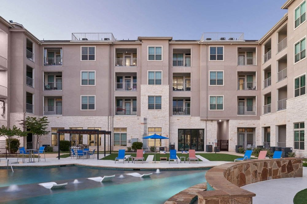 a swimming pool with a fountain in front of an apartment building