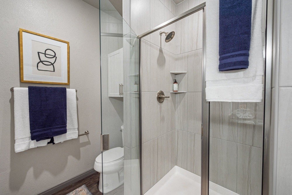 a bathroom with a shower and a toilet and blue towels