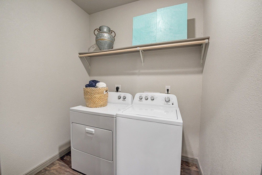 the laundry room has a white washer and dryer and a shelf above it