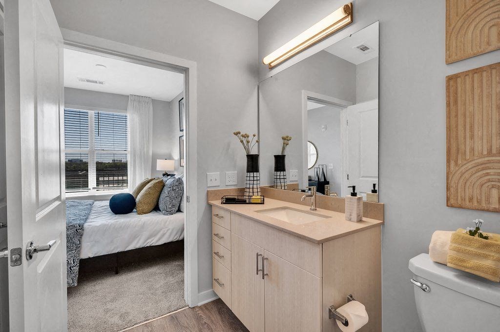 a bathroom with a sink and a mirror and a bedroom