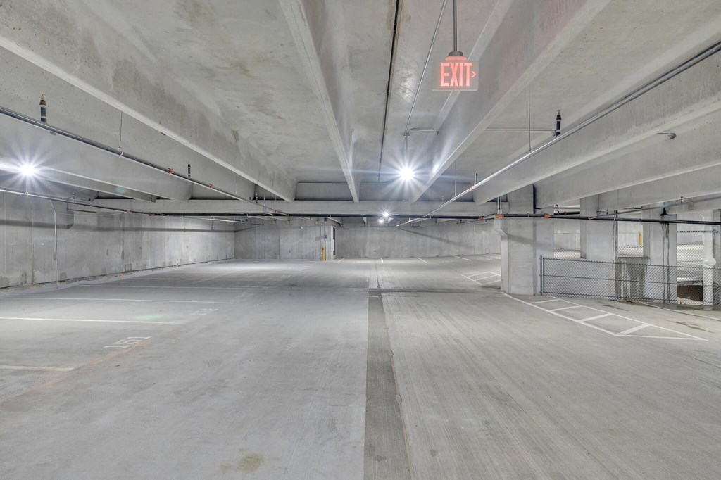 an empty parking garage with an exit sign in the ceiling