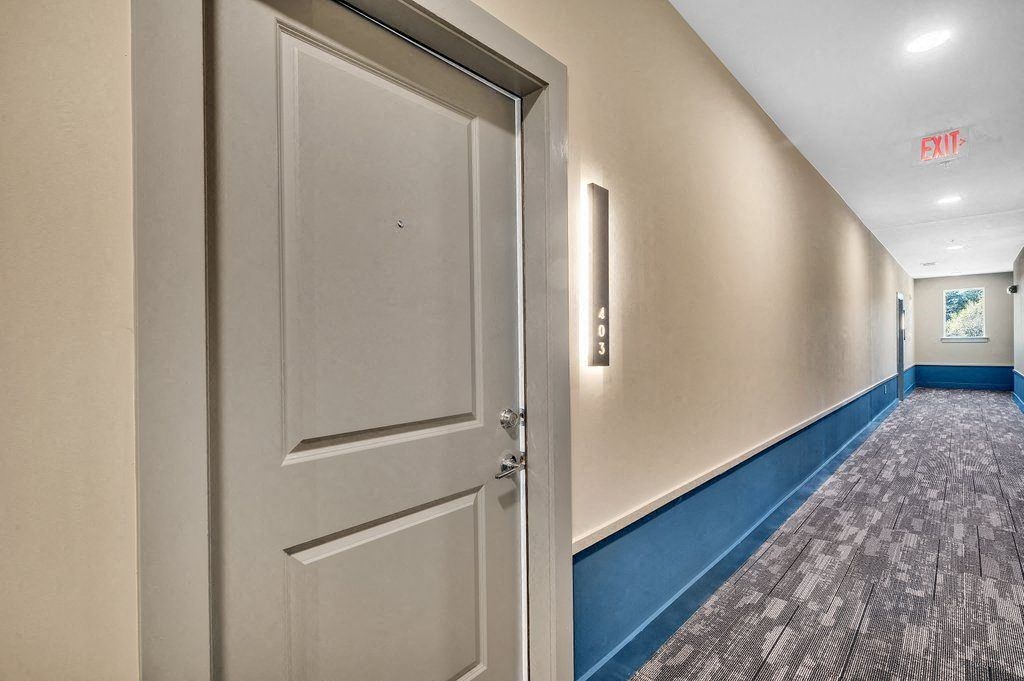 a white door in a hallway with a blue wall and a door to a room