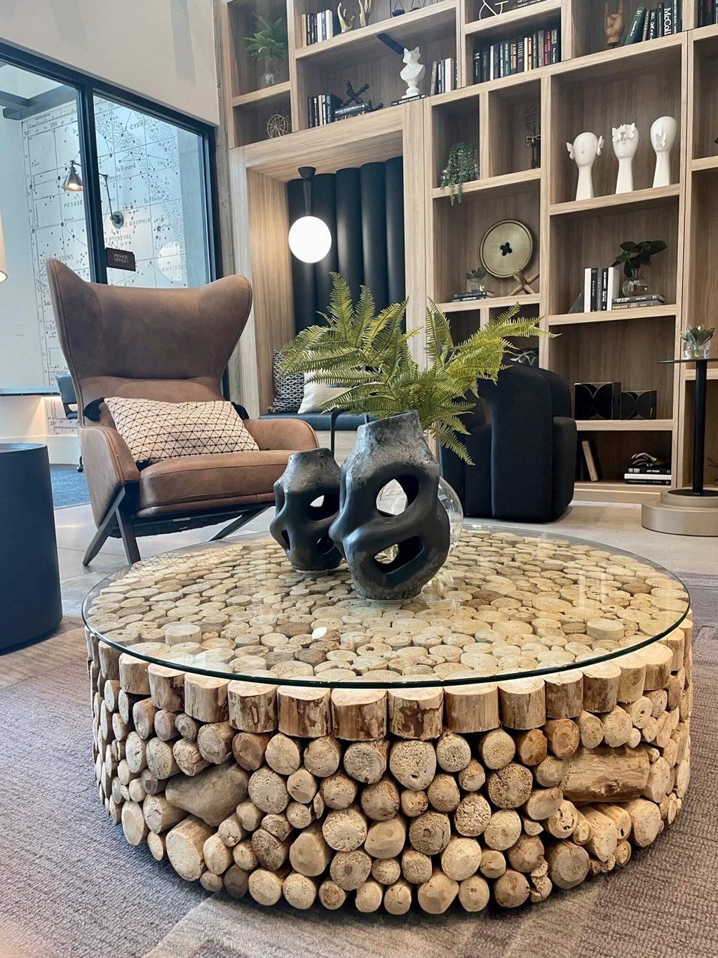a coffee table made out of logs with two black vases on it