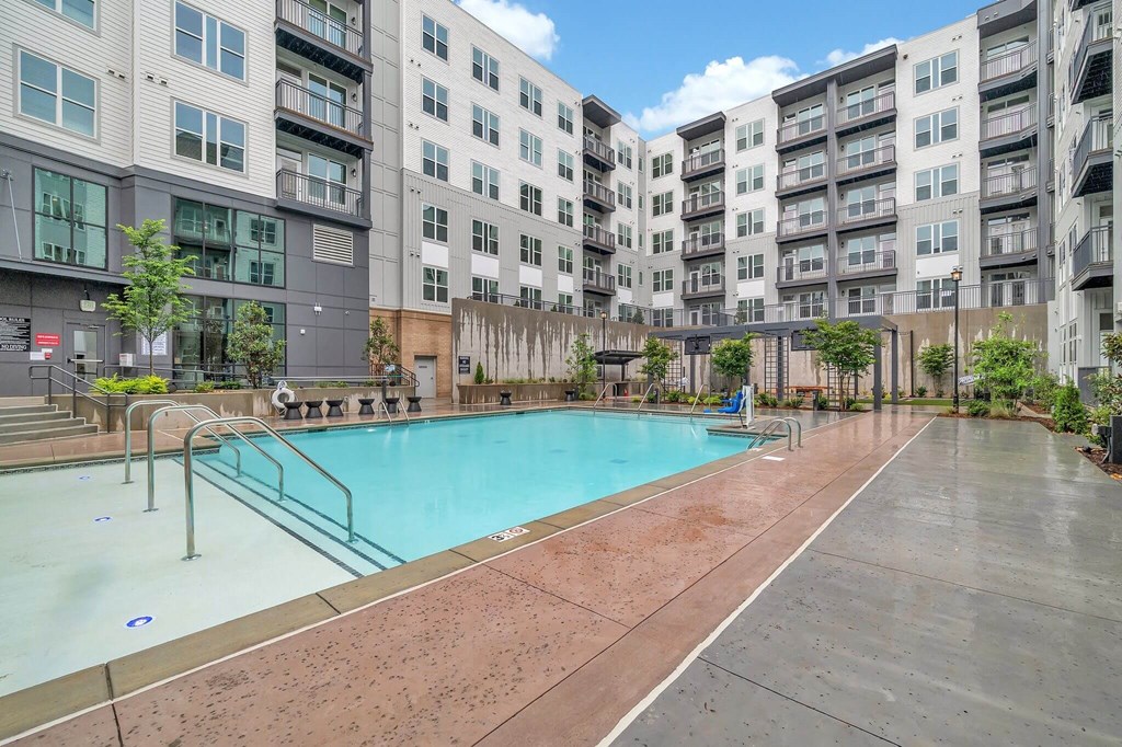 an apartment swimming pool with an apartment building in the background