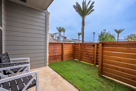 the backyard has a lawn and a fence with palm trees