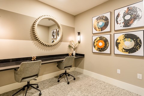 an office with two chairs and a desk with a mirror and pictures on the wall