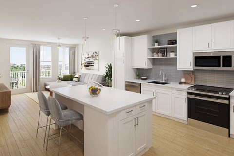 a white kitchen with a large island and a living room